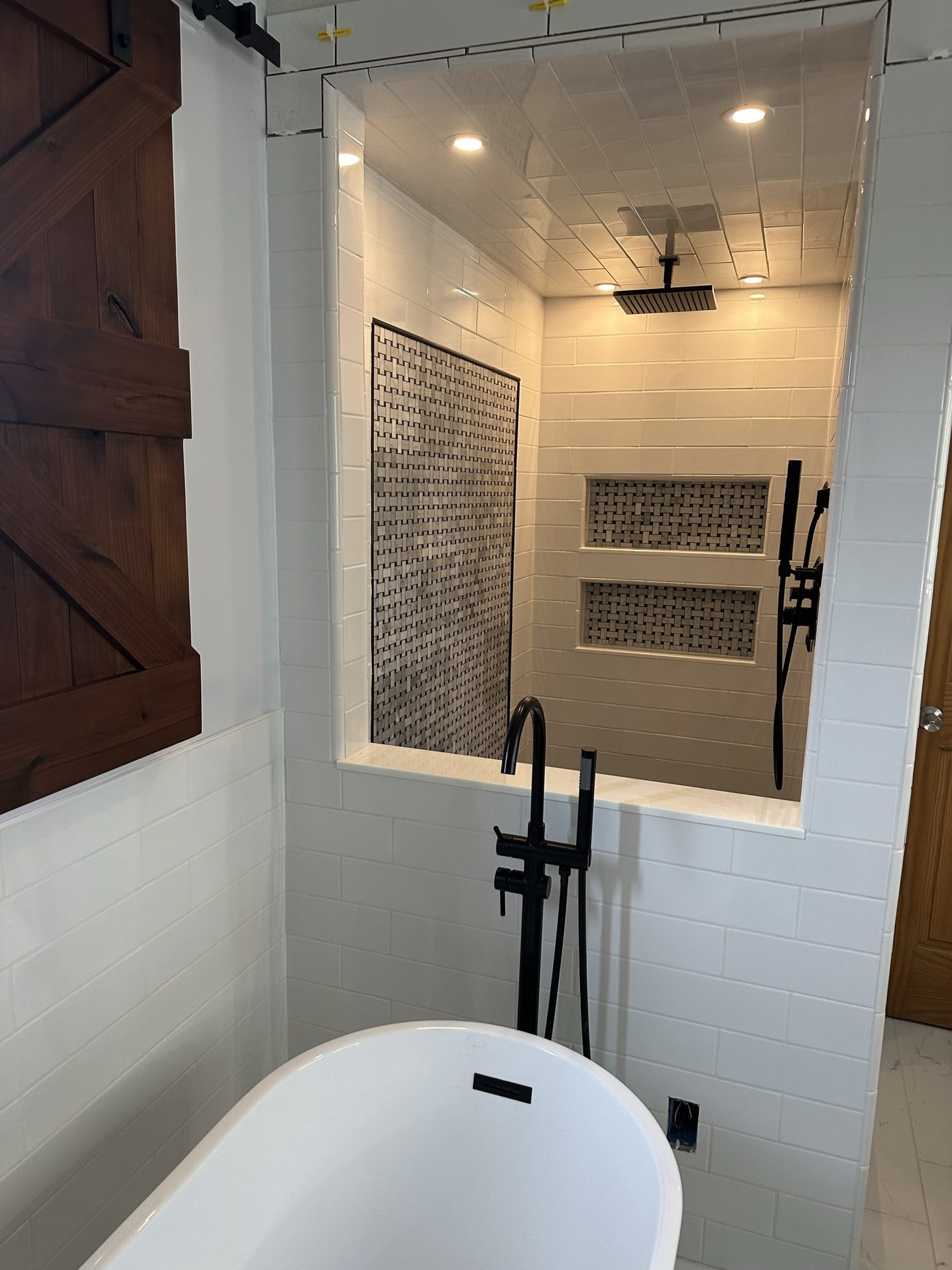 Remodeled bathroom with a freestanding tub and a lit walk-in shower with tiled niches