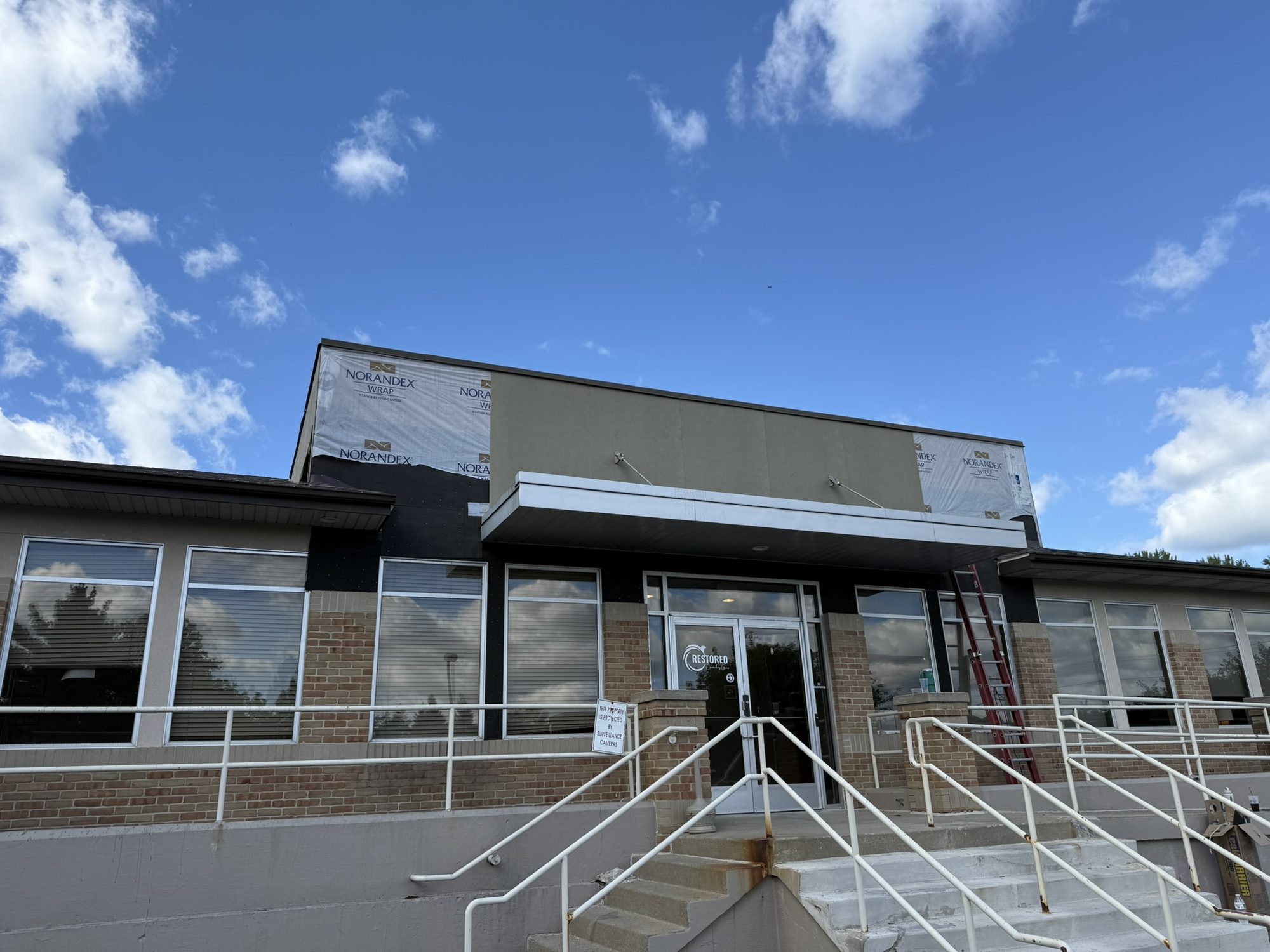 Renovated commercial storefront facade with new exterior panels and entry railings