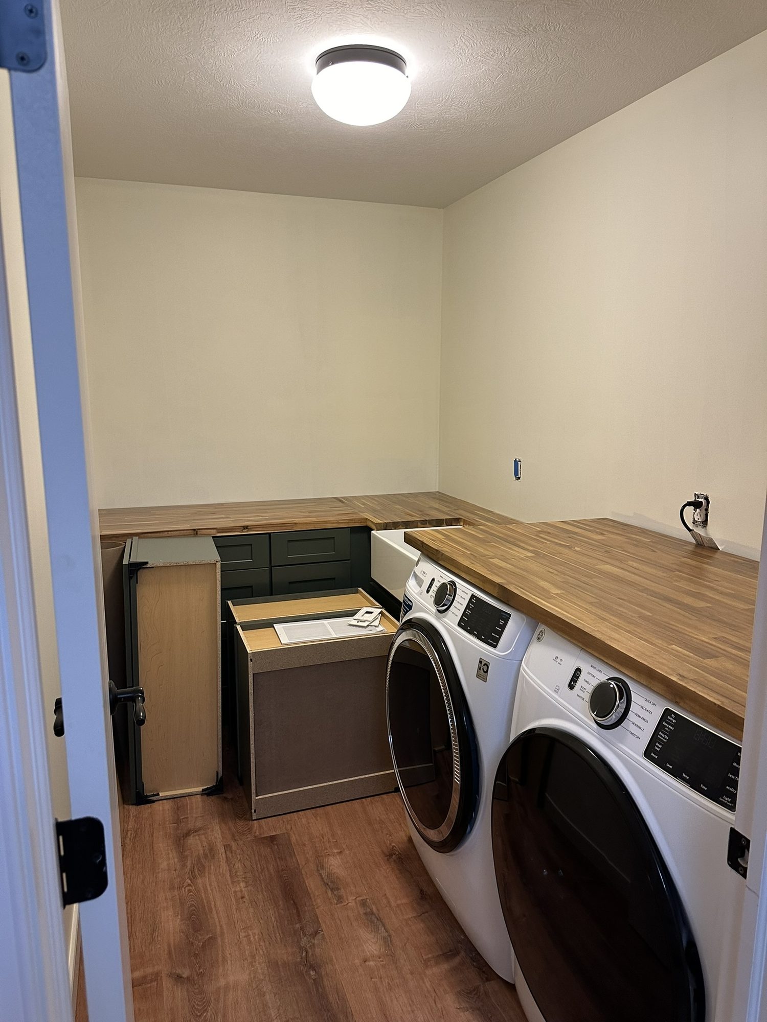 Laundry room with butcher-block counter, front-load washer and dryer, and wood-look LVP flooring