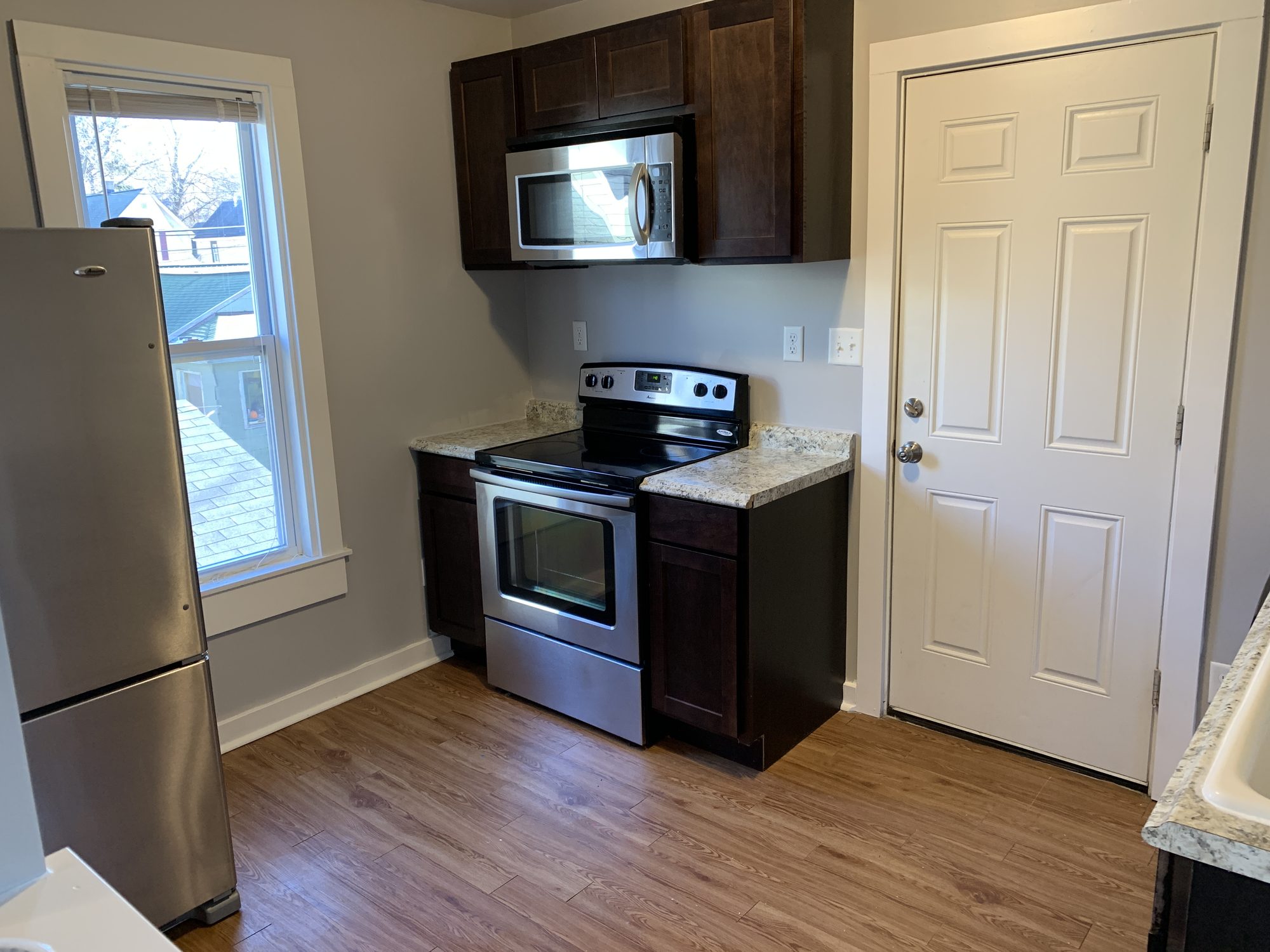 Kitchen with dark cabinets, stainless appliances, and wood-look LVP flooring
