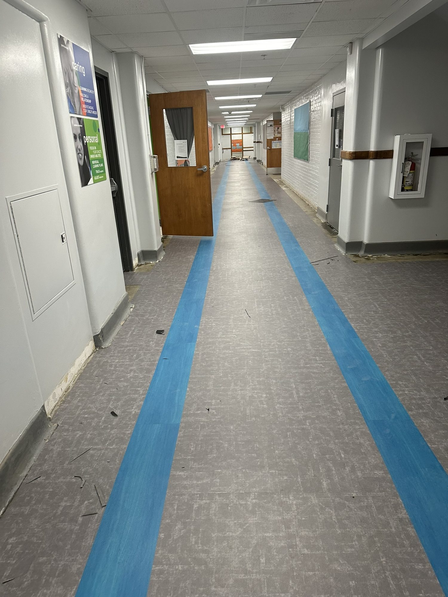 Gray glue-down LVT corridor floor with blue inlay lines