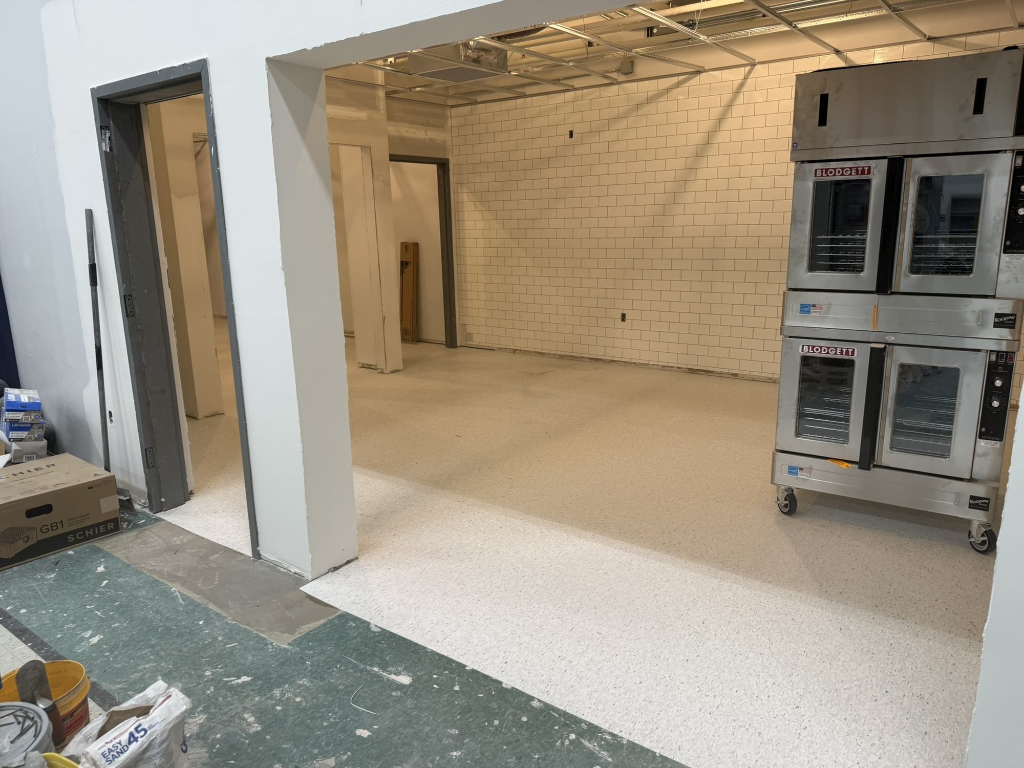 Commercial kitchen with new white speckled VCT installed and cooking equipment staged