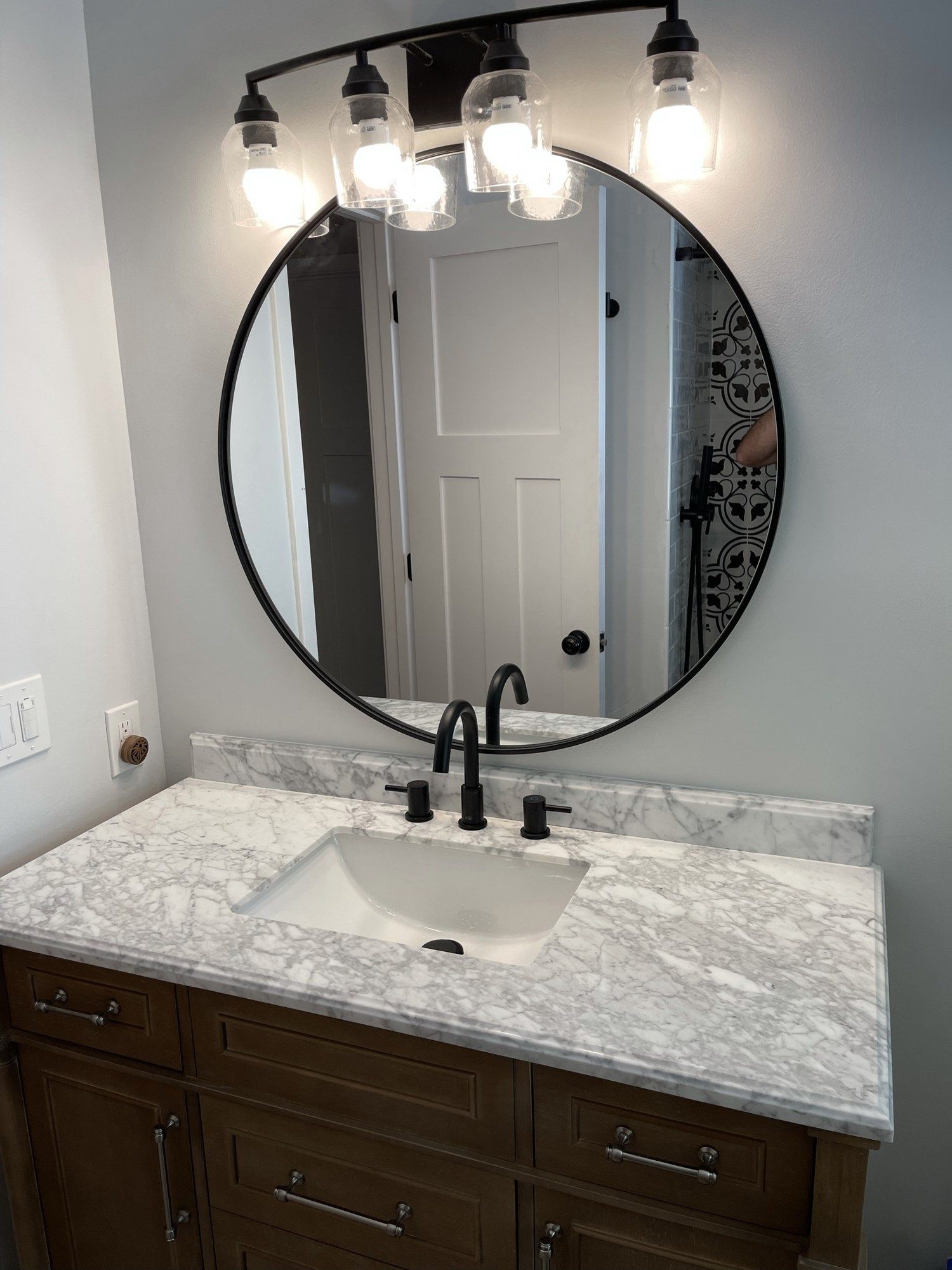 Bathroom vanity with marble-look countertop and round black-framed mirror