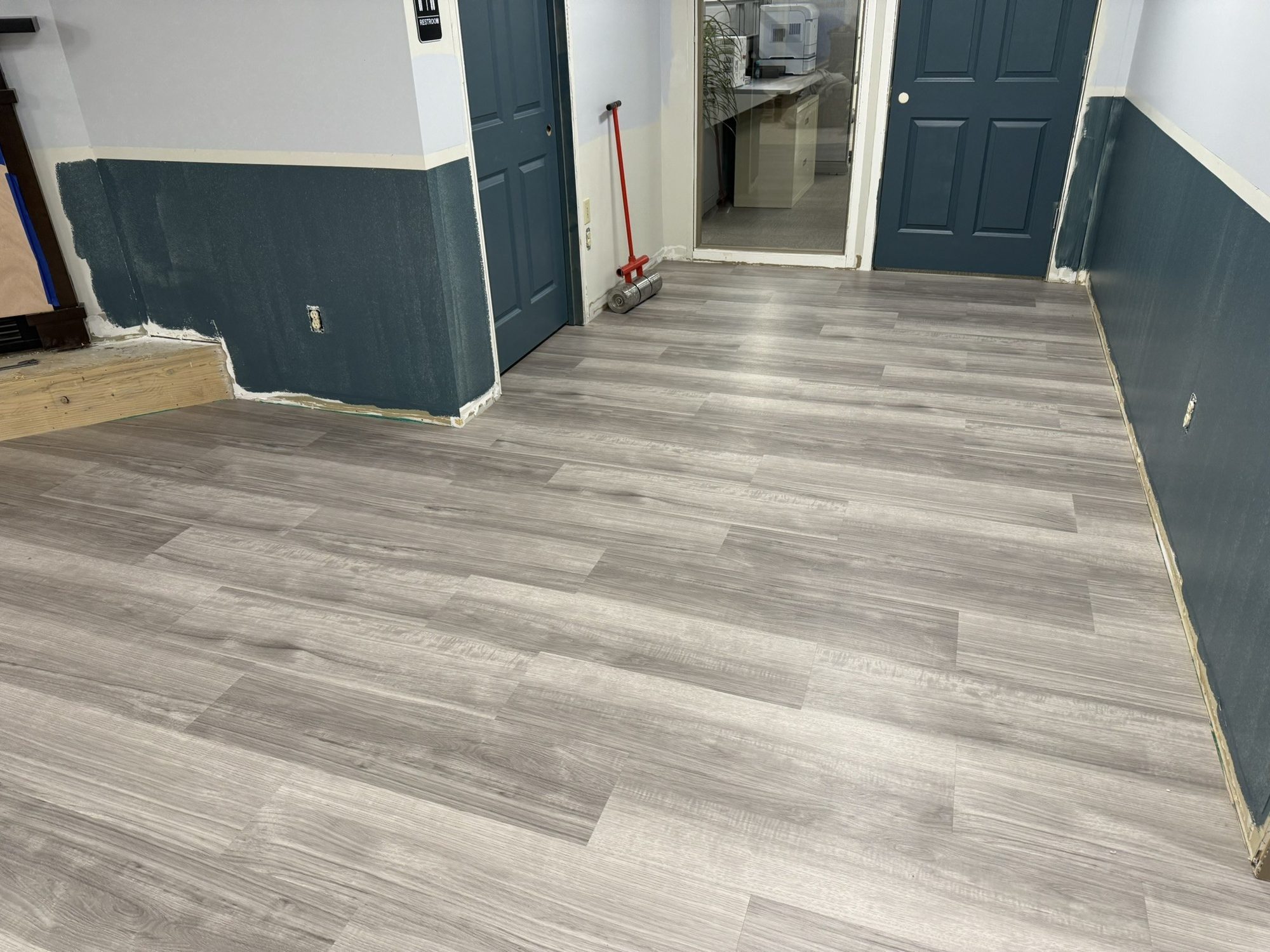 Gray wood-look LVT in a hallway with navy wainscot