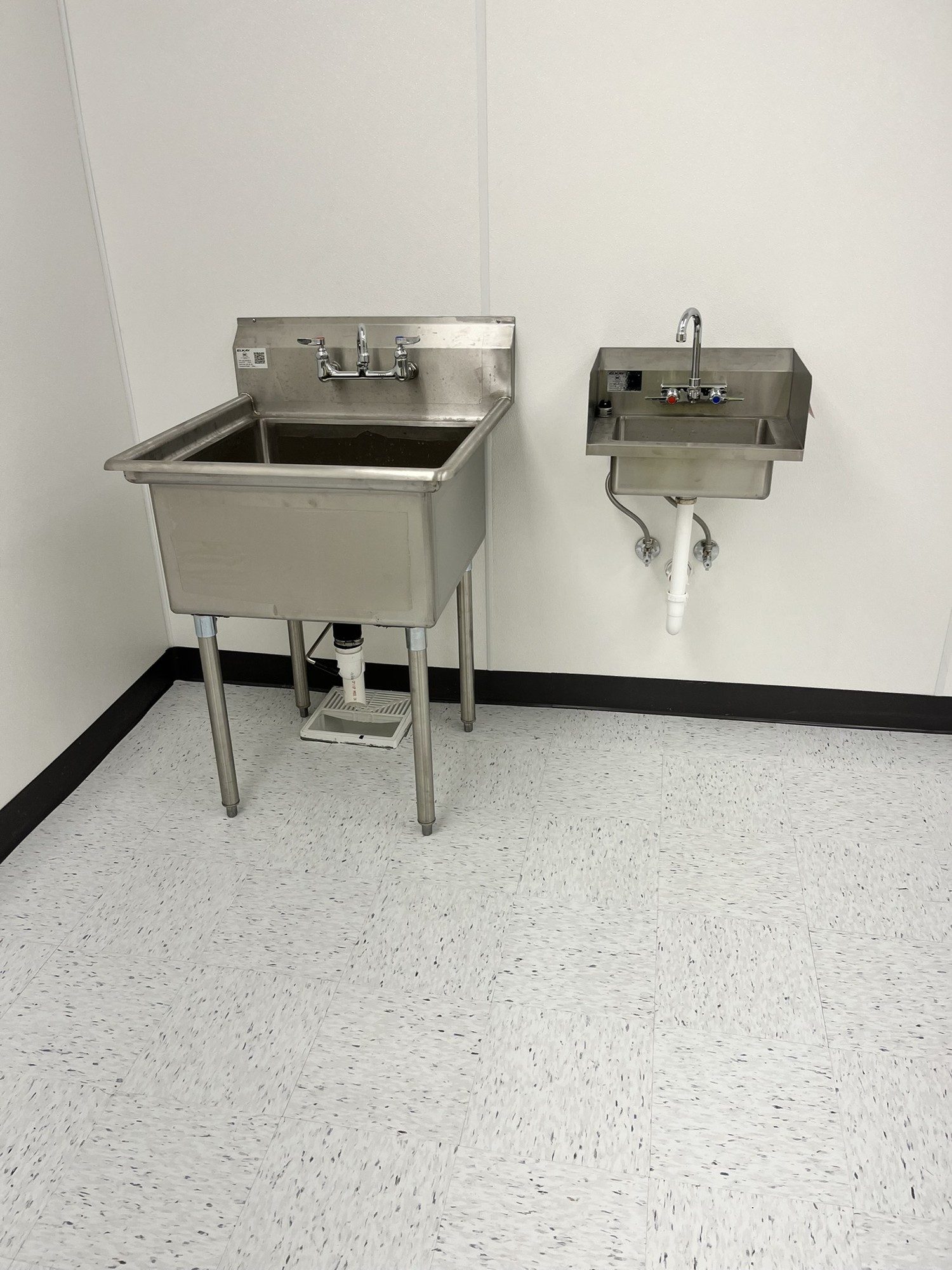 Speckled VCT flooring beneath utility sinks